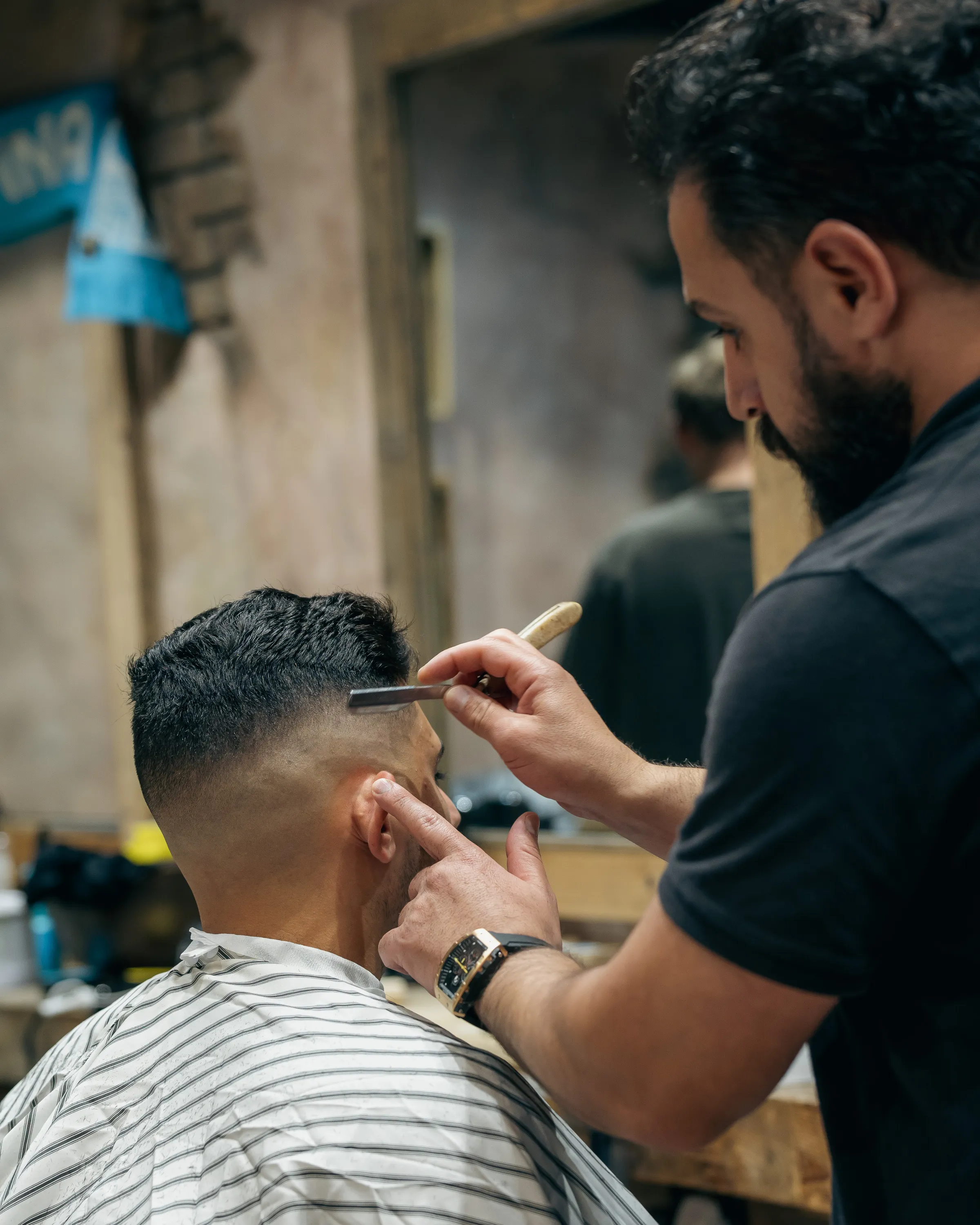 Barber detailing a skin fade with a straight razor