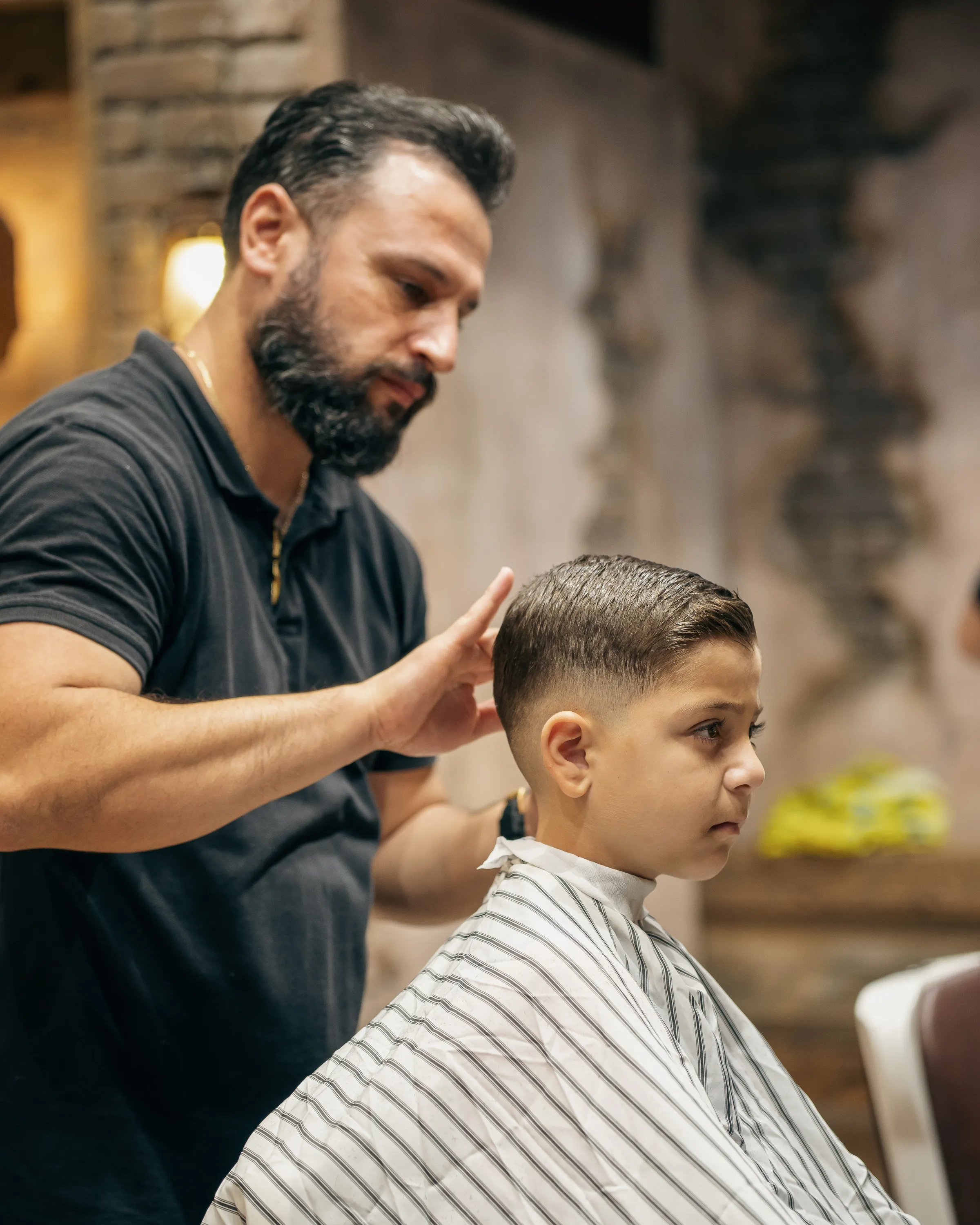 Young boy getting a fade and side part
